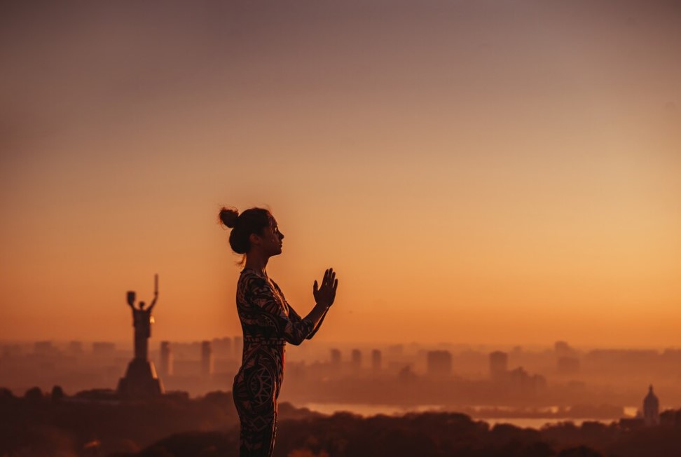 Imagem de mulher concentrada meditando com as mãos unidas em lugar místico Imagem de mulher concentrada meditando com as mãos unidas em lugar místico