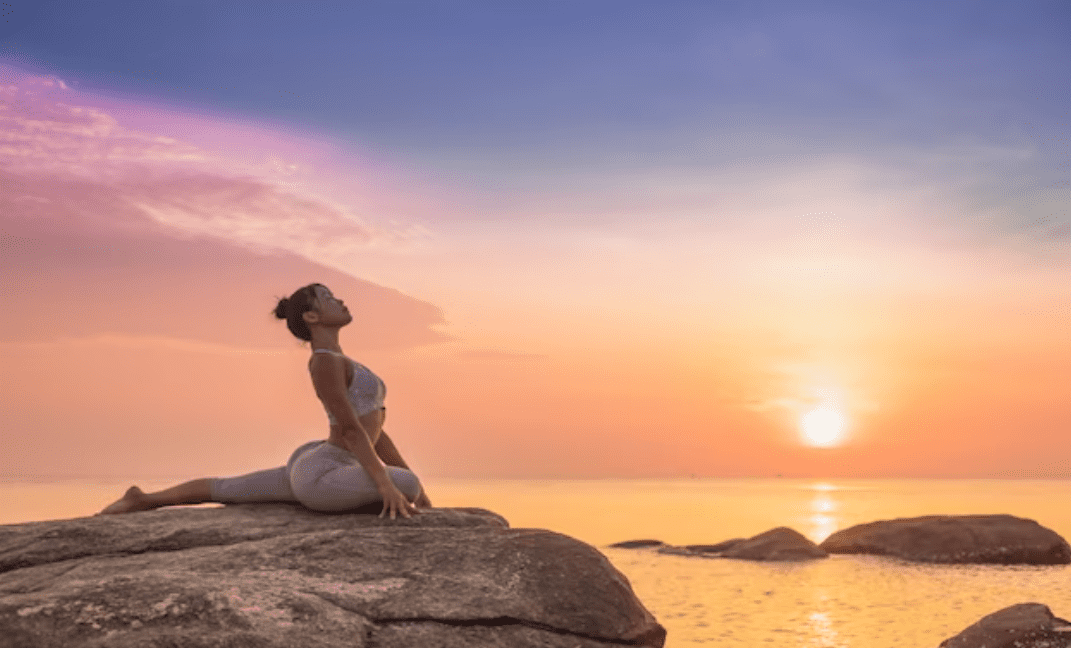Mulher jovem praticando Yoga ao ar livre nas pedras em frente a praia